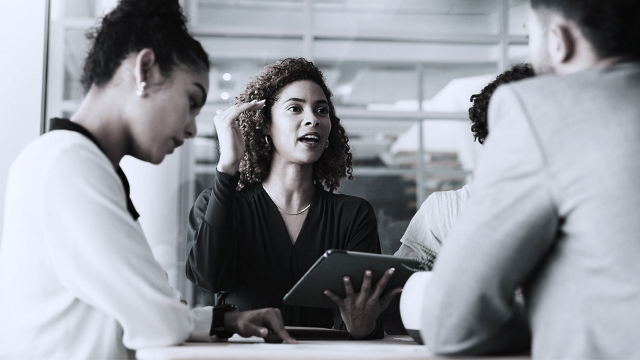 Female executive sitting at table, presenting to a team