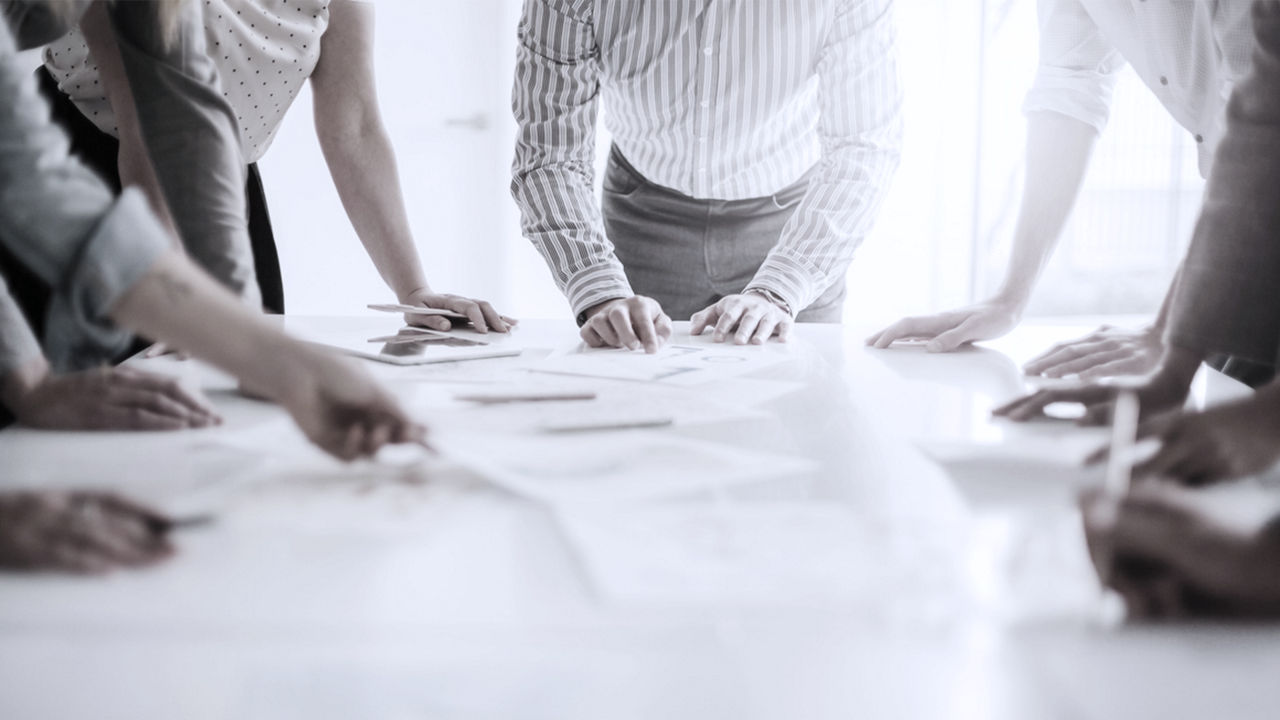 5 business leaders standing around a table planning