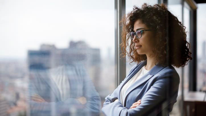 A business woman standing in front of a window with her arms crossed.