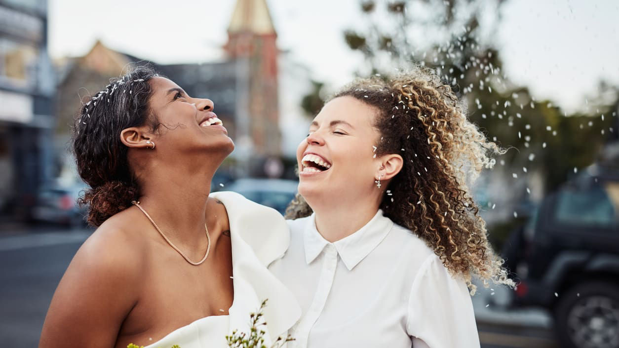 Two brides laughing in the street.