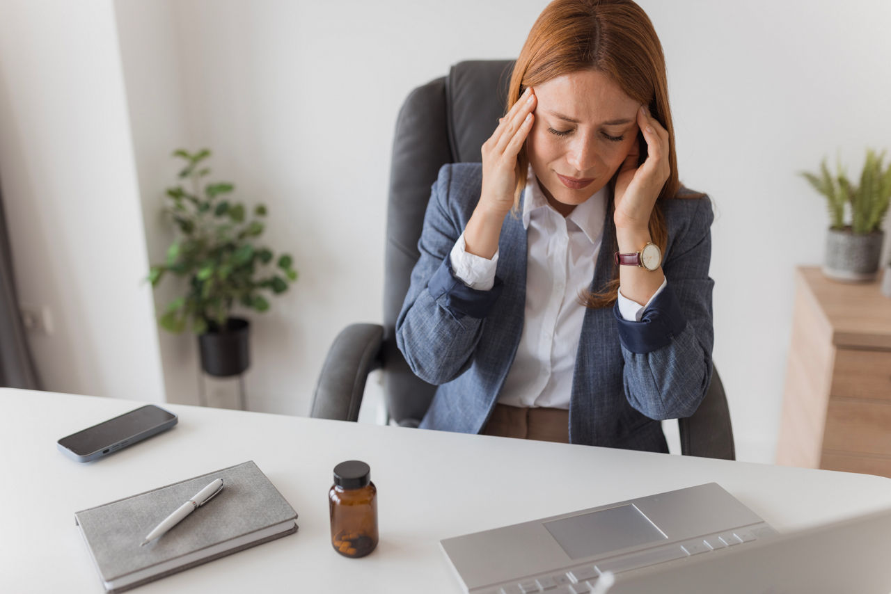 Businesswoman having a bad headache at work, touching temples and closing eyes