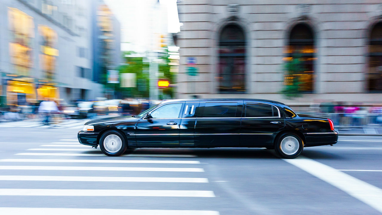 A black limo driving down the street.