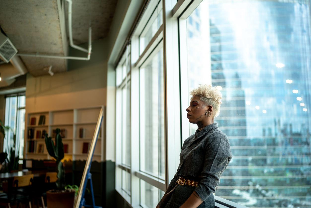Worried businesswoman leaning against window at office