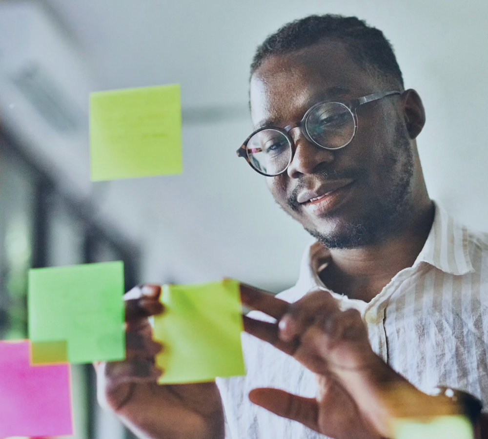 Office working aligning post-it notes on a glass board.