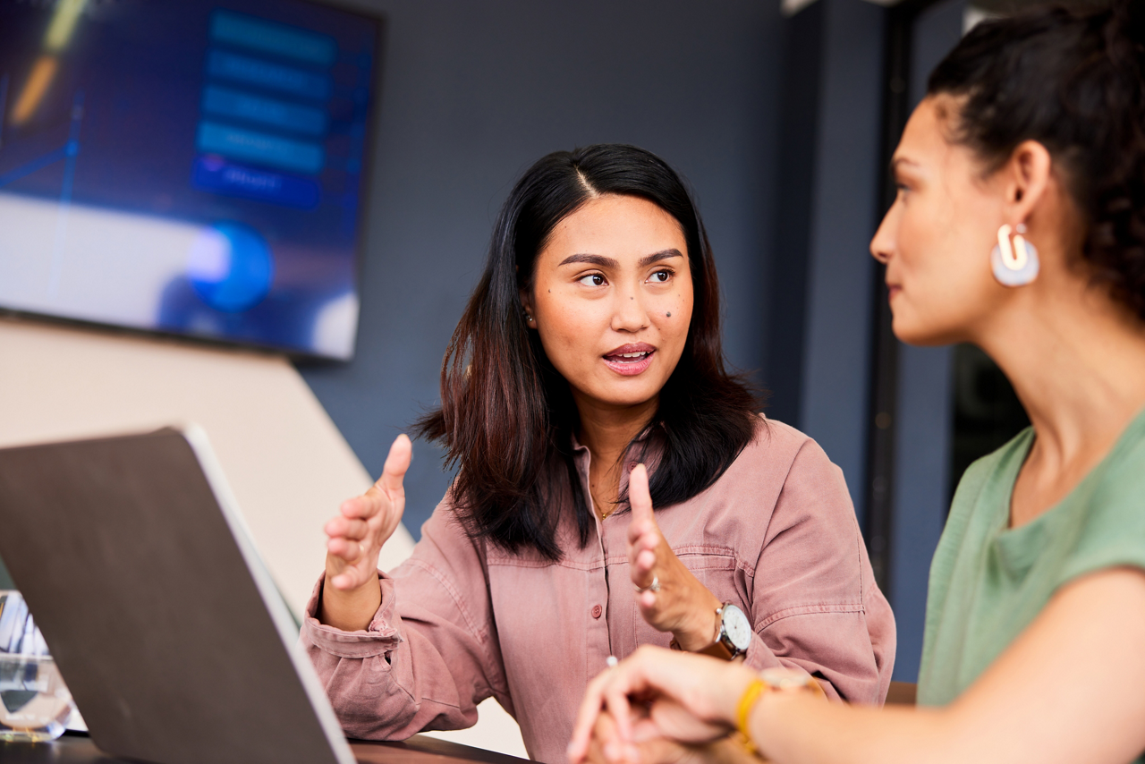 Two mid adult businesswomen discussing in meeting, woman in her 30s with serious expression, talking