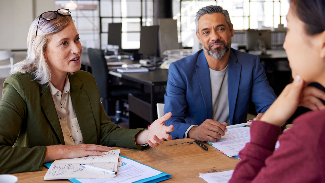 Coworkers discussing a meeting agenda in an office setting.