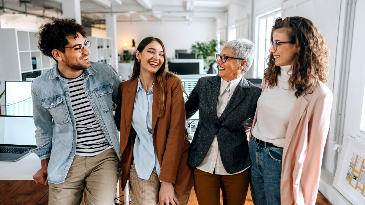 Coworkers laughing and smiling while posing for a group photo.