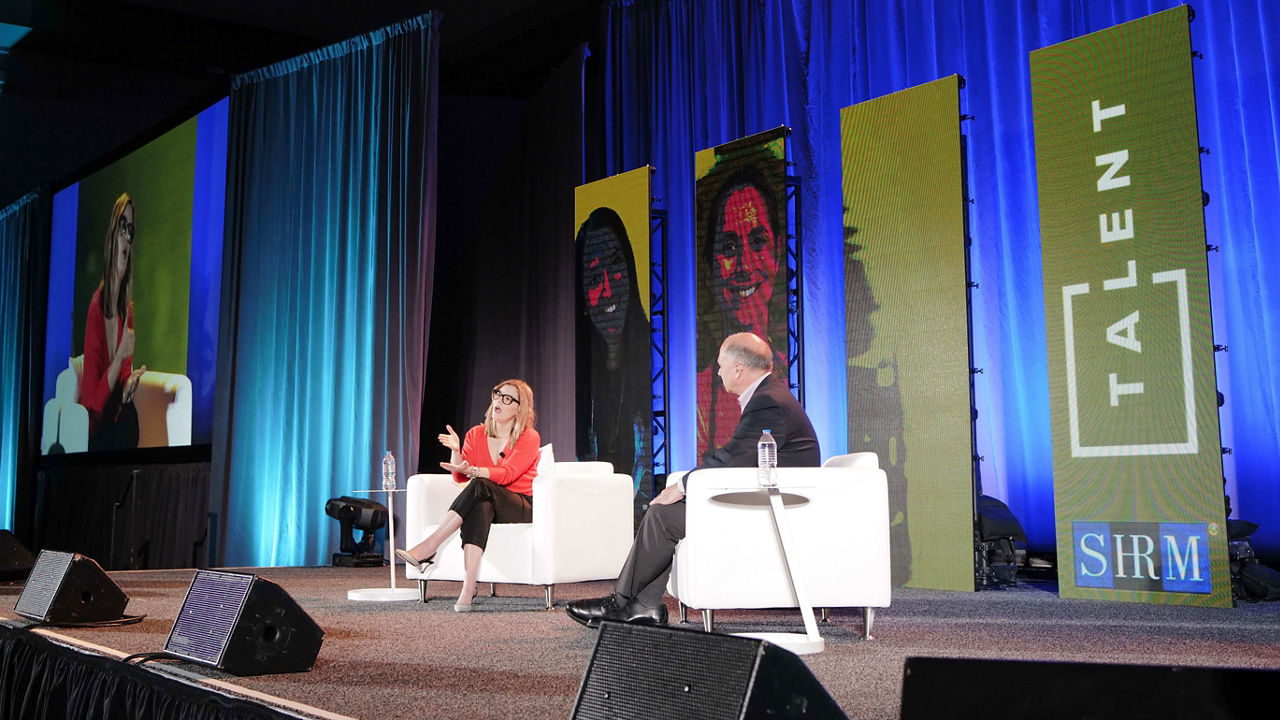 Two people on stage at a conference.