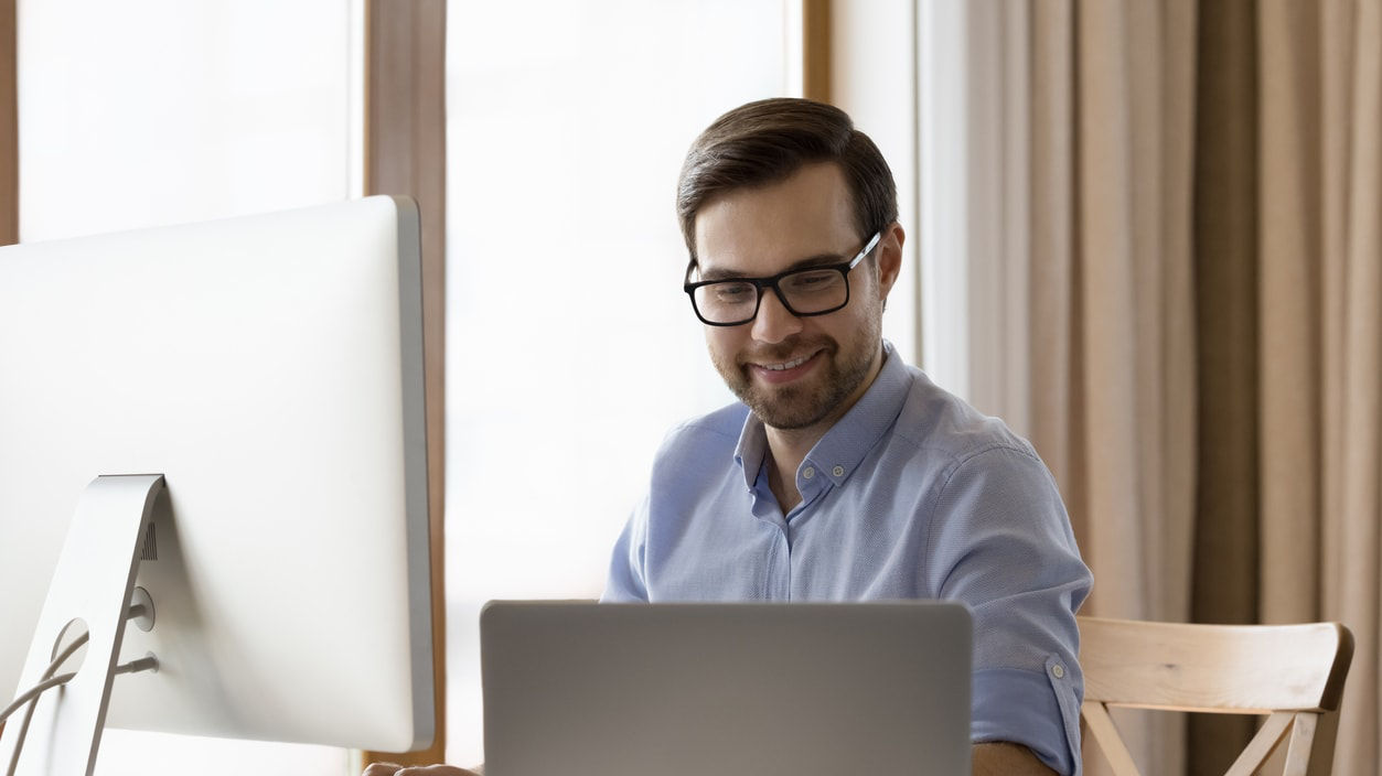 A man sitting at a desk with a laptop in front of him.