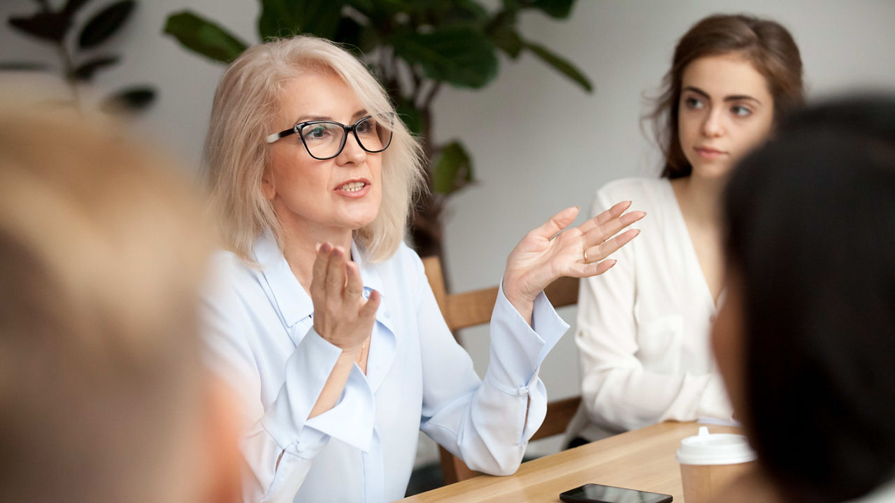 A group of women sitting at a table and talking to each other.