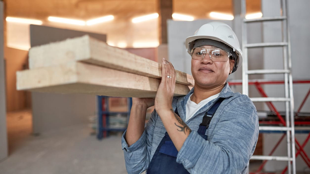 A construction worker holding a piece of wood.