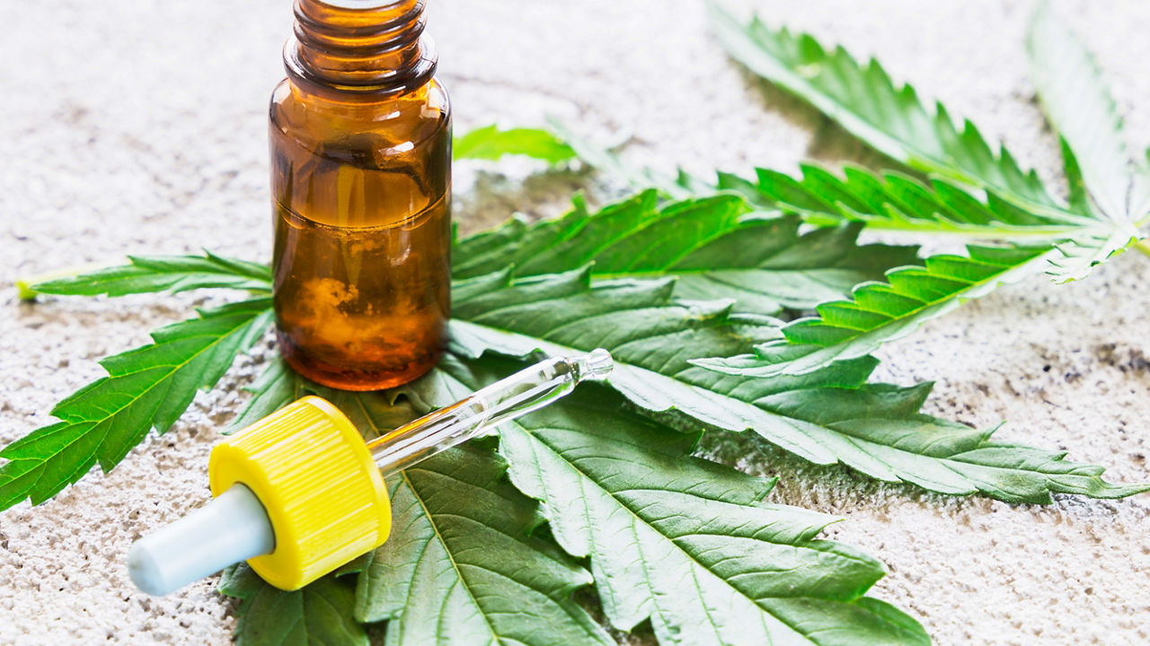 Cbd oil and cannabis leaves on a white background.