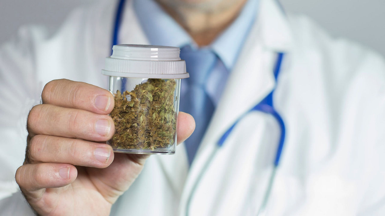 A doctor holding a jar of marijuana.