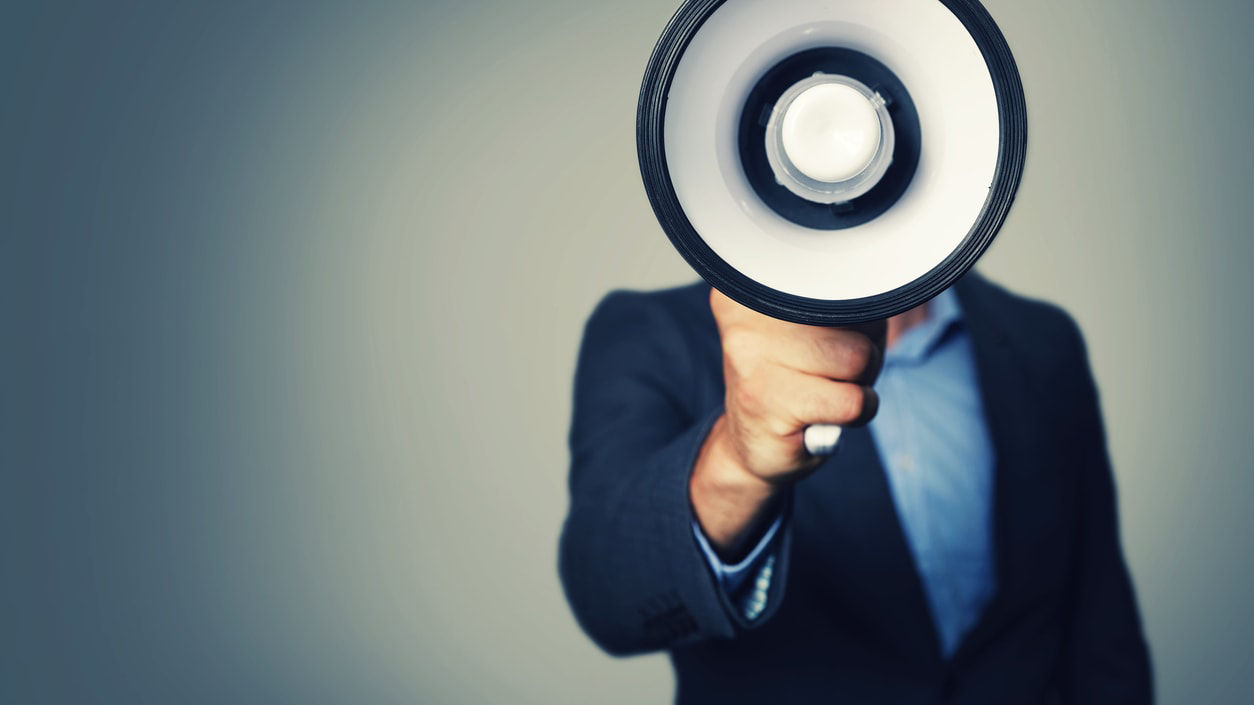 A businessman is holding a megaphone.