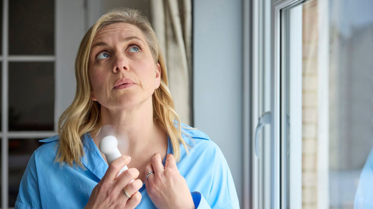 A woman holding a fan to help cool off