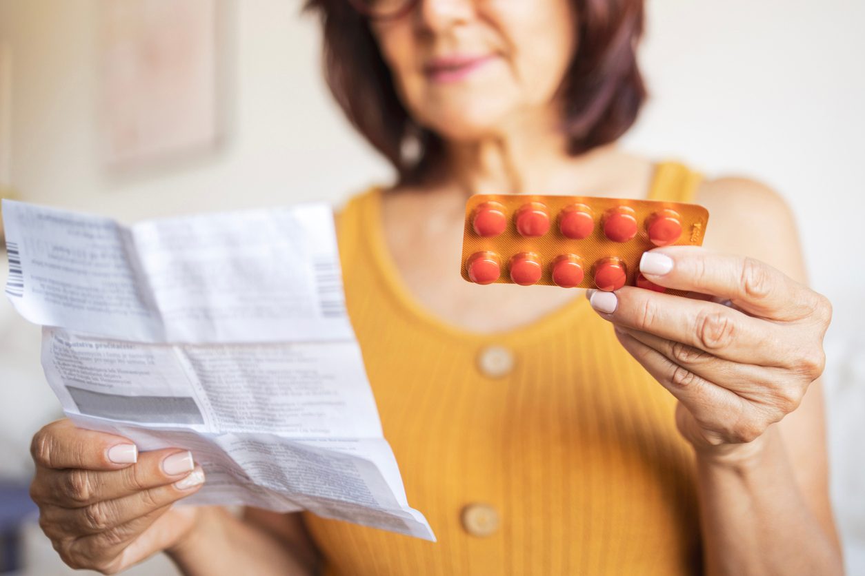 woman looking at hormone replacement pills and instructions