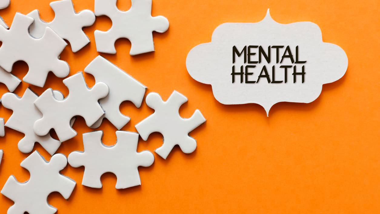 Mental health puzzle pieces on an orange background.