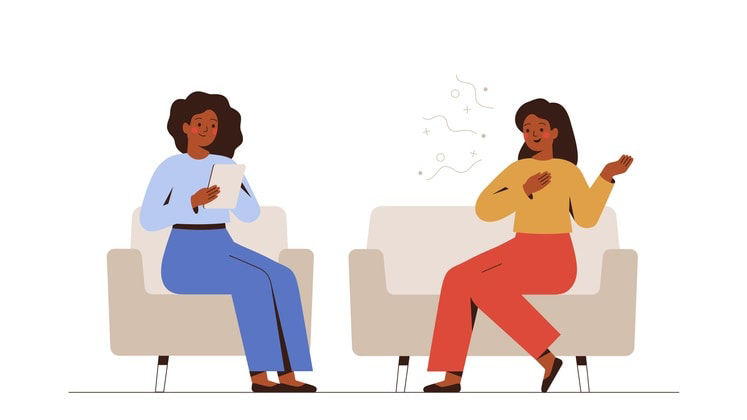 Two women sitting on chairs and talking to each other.