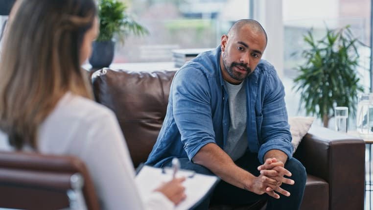 A man sitting on a couch talking to a therapist.