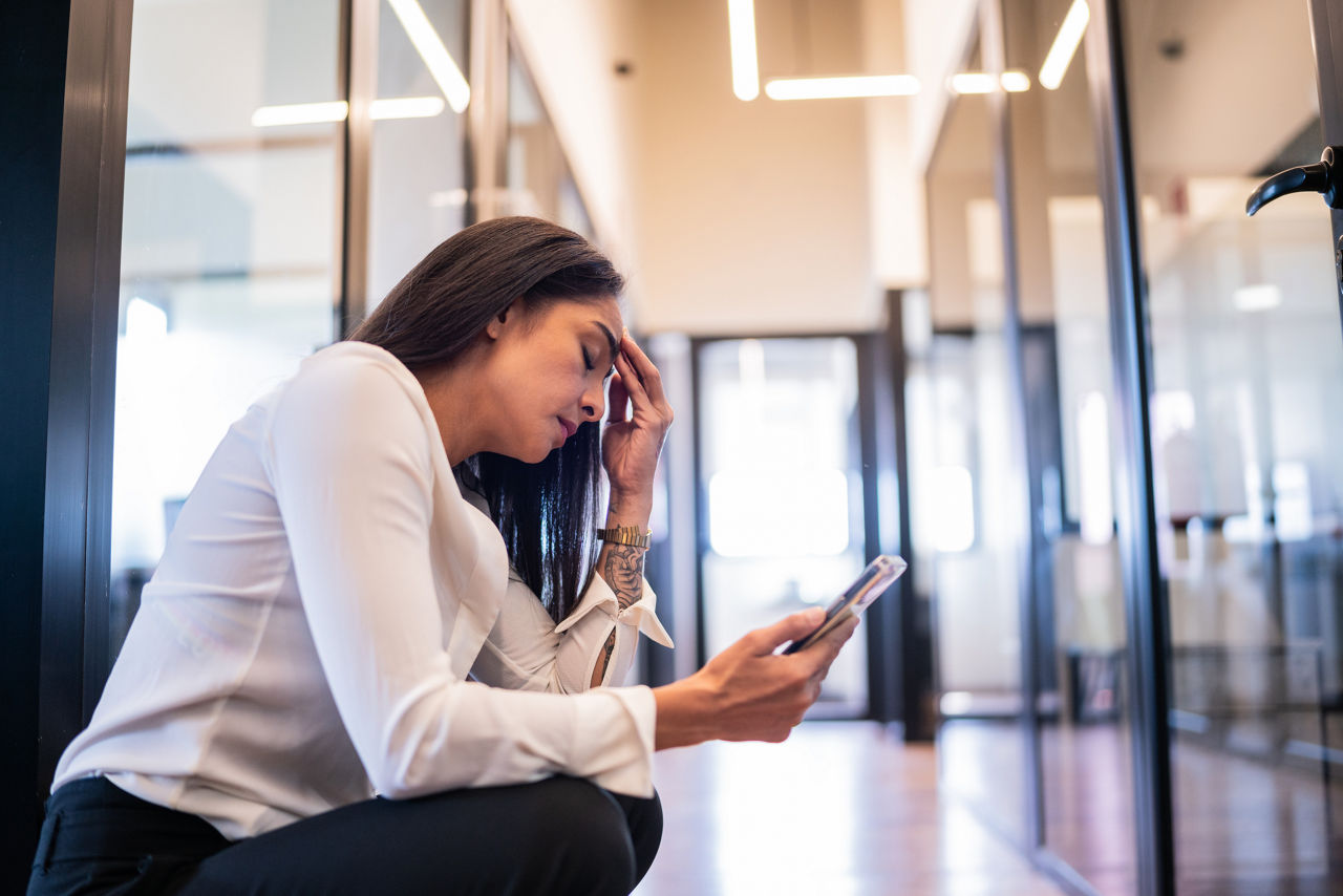 Worried businesswoman using a mobile phone while taking a break on work at office