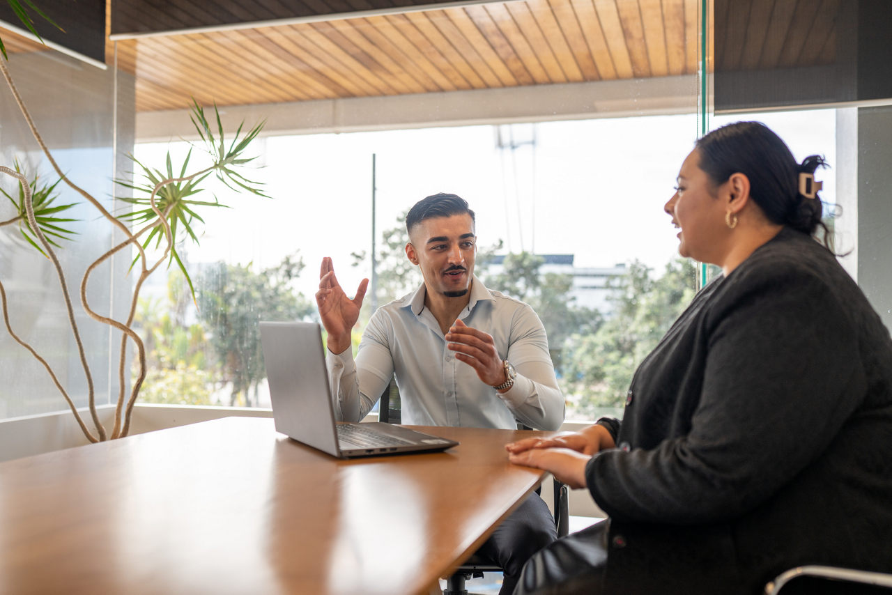 A young professional talking with a colleague in front of laptop notes