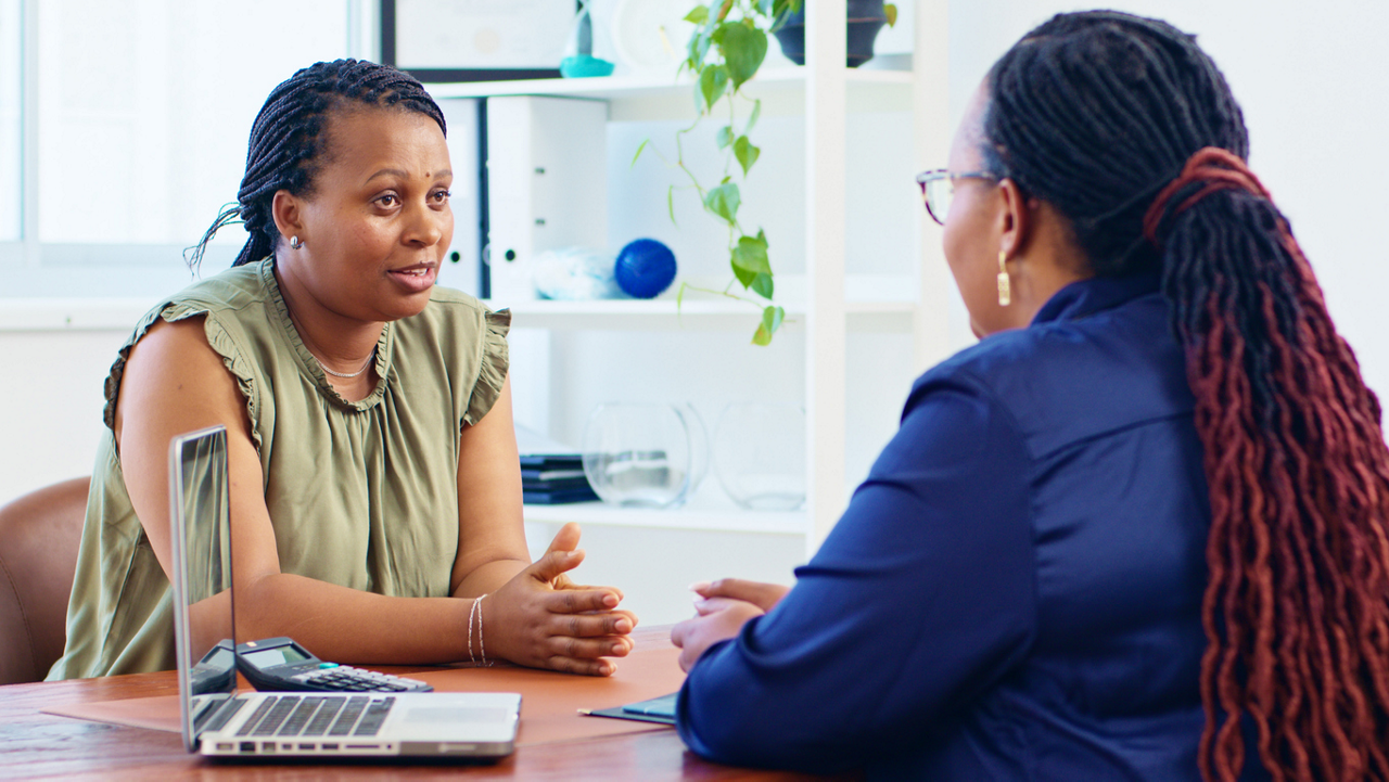 Two women engage in a professional consultation, exchanging ideas in a modern office setting. The meeting highlights communication and collaboration.