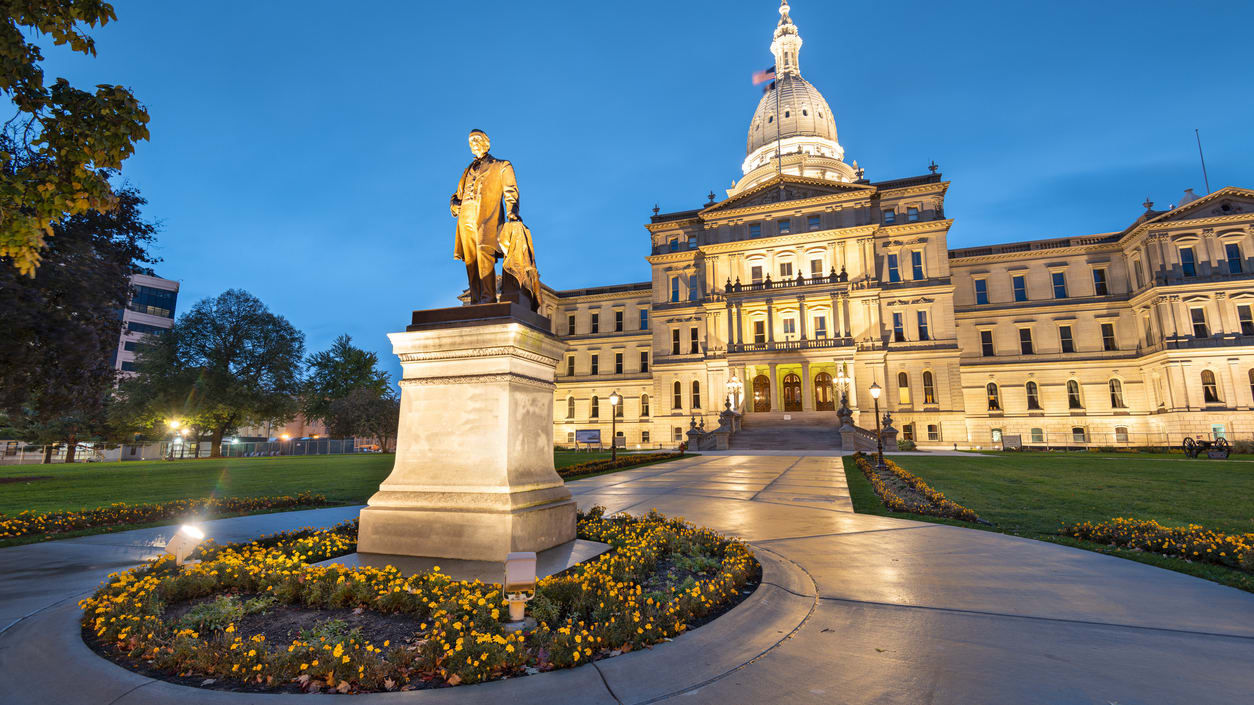 A statue in front of the state capitol building at dusk.