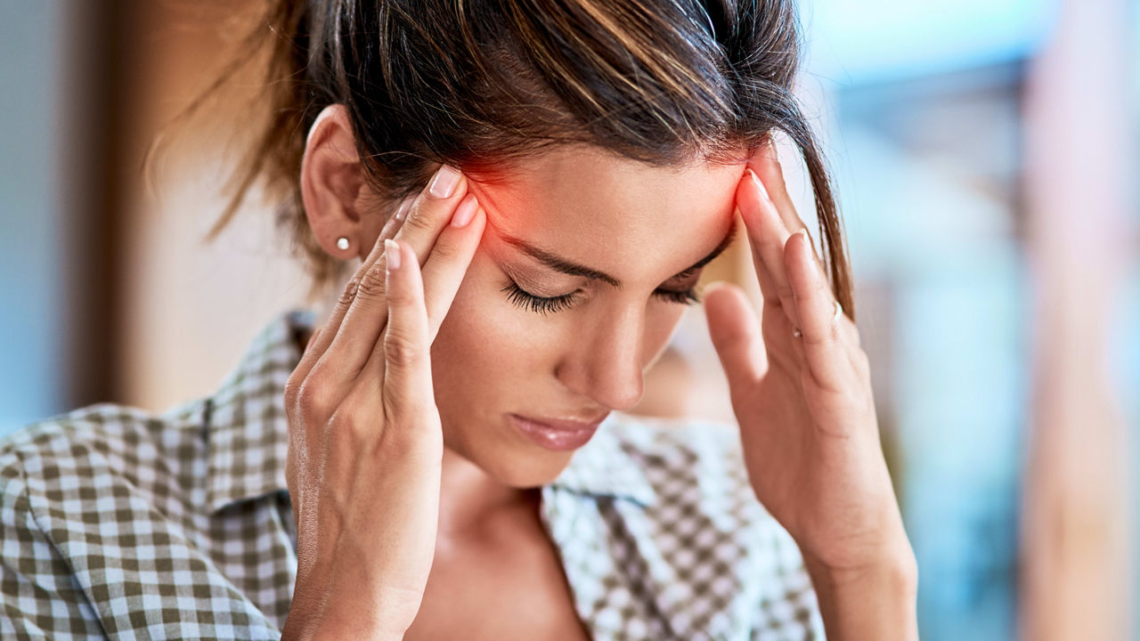 A woman is holding her head with her hands.