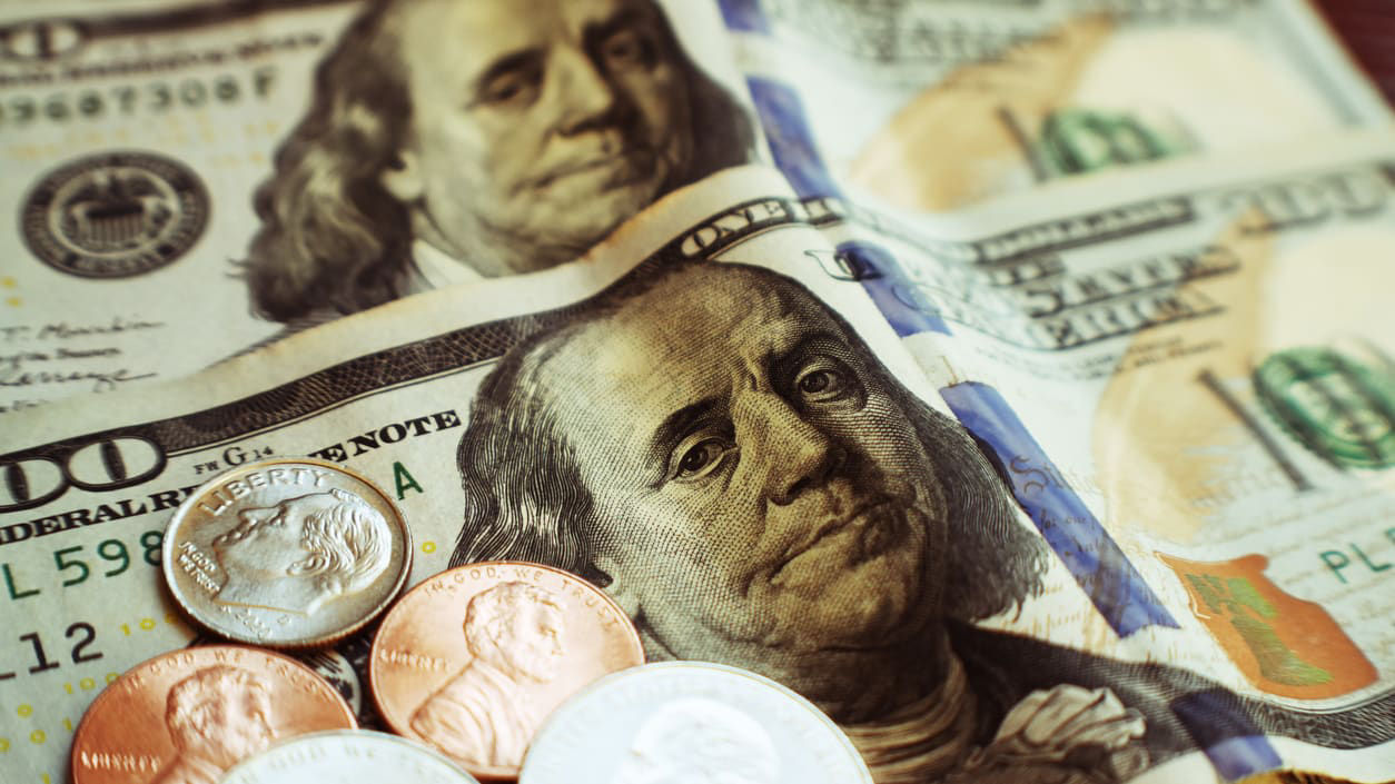A stack of us dollar bills and coins on a table.