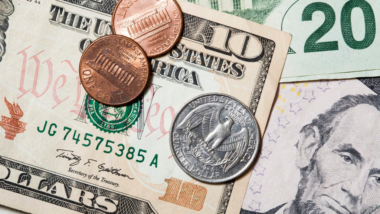 A stack of dollar bills and coins on a white background.