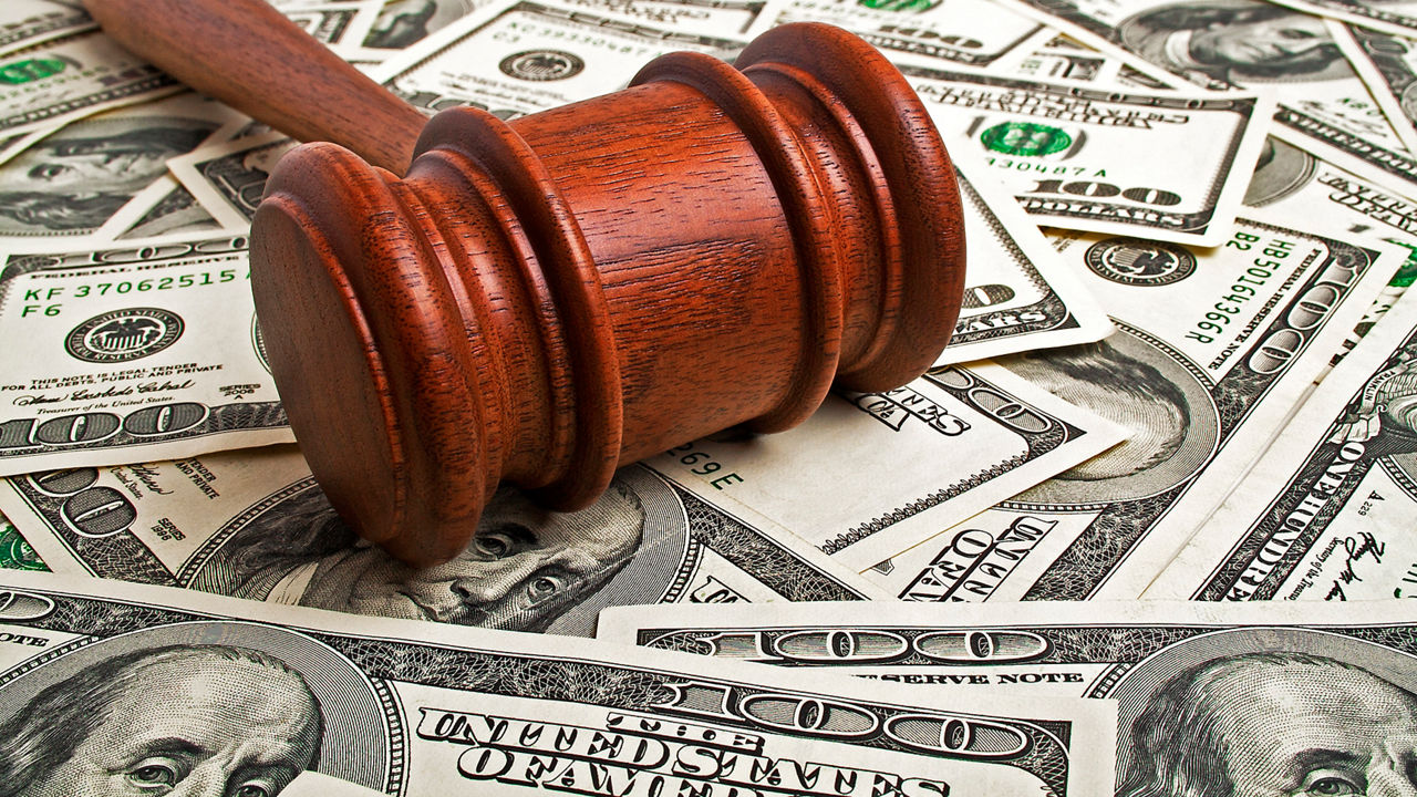 A wooden gavel on top of a pile of money.