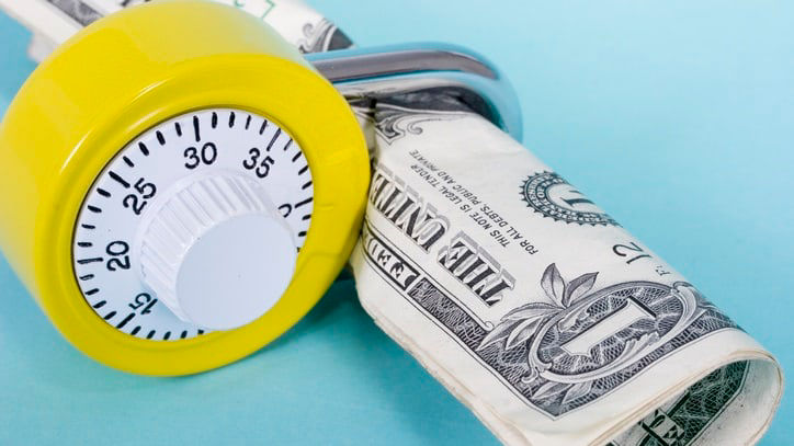 A yellow timer sitting on top of a stack of dollar bills.