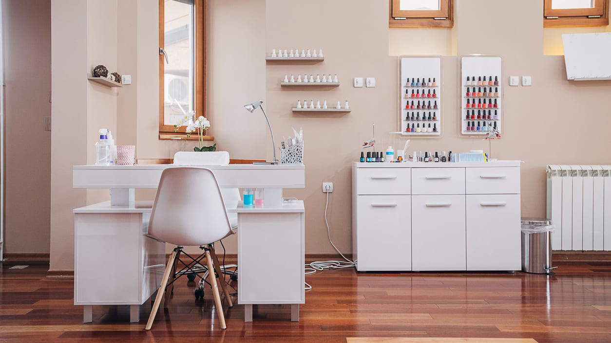 A nail salon with a white chair and shelves.