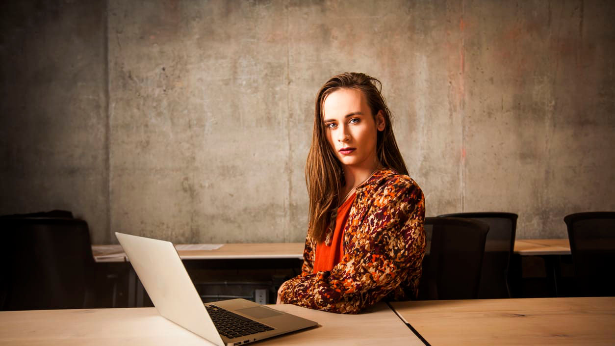 A young woman sitting at a desk with a laptop.