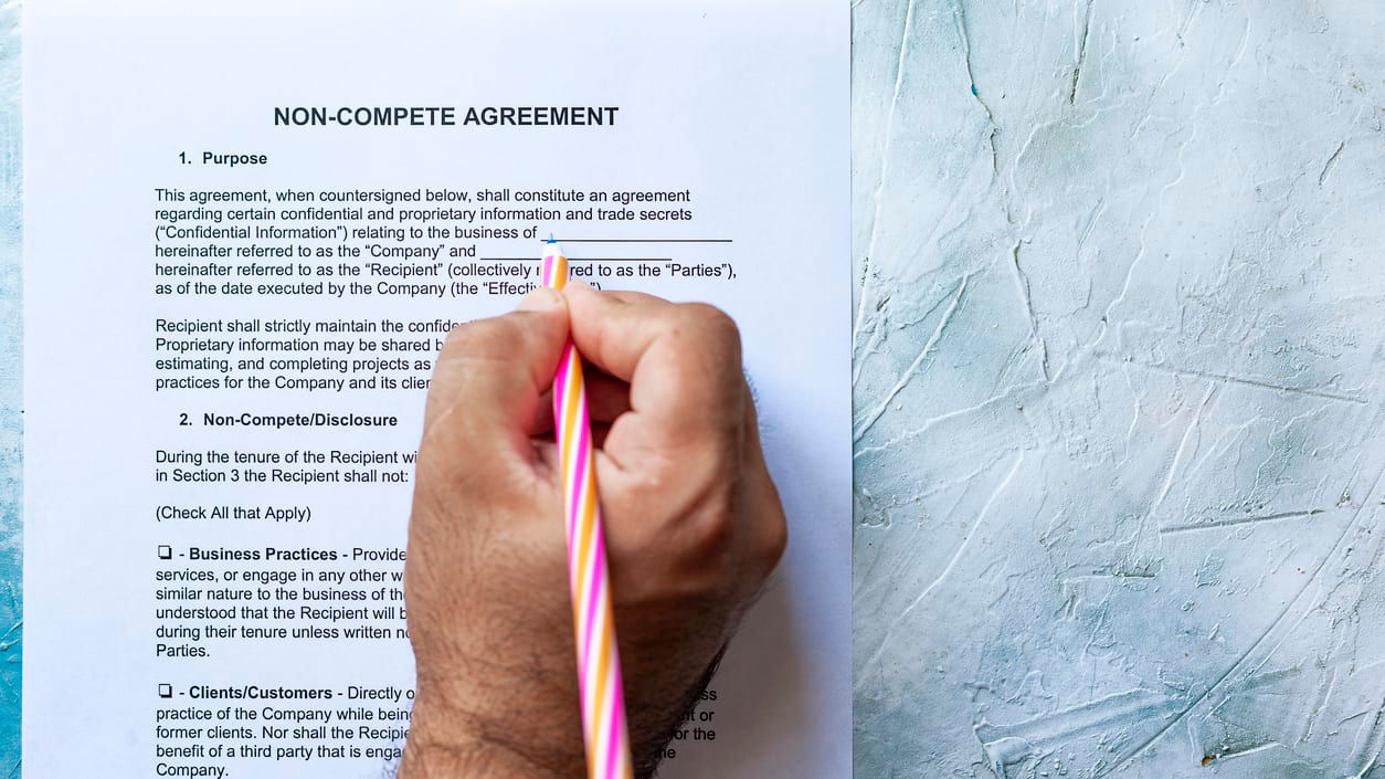 A person writing on a piece of paper with a pen.