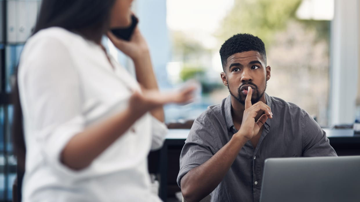 A man and woman talking on the phone in an office.