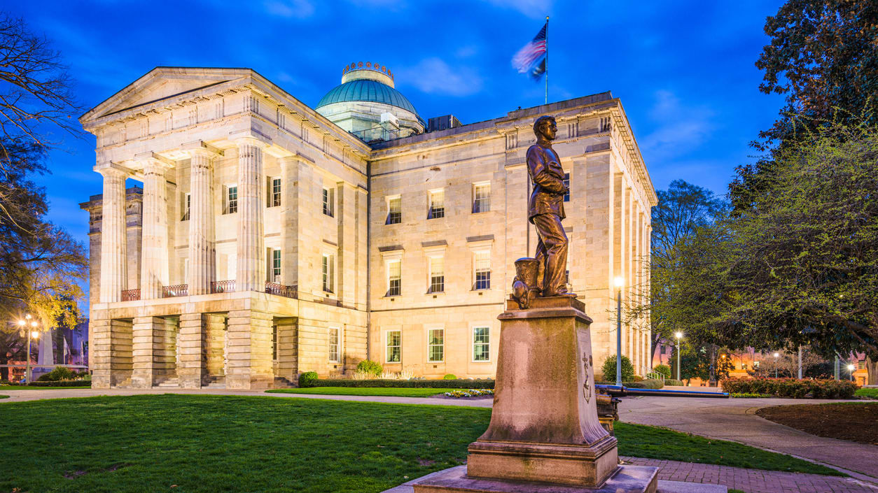 A statue in front of a large building at dusk.