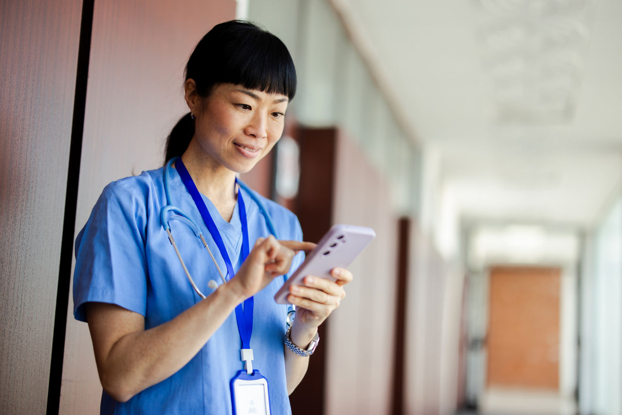 Asian medical professional managing digital tasks with mobile phone in a healthcare setting