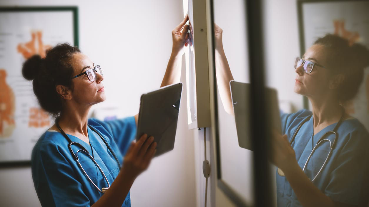A nurse looking at a tablet in a mirror.