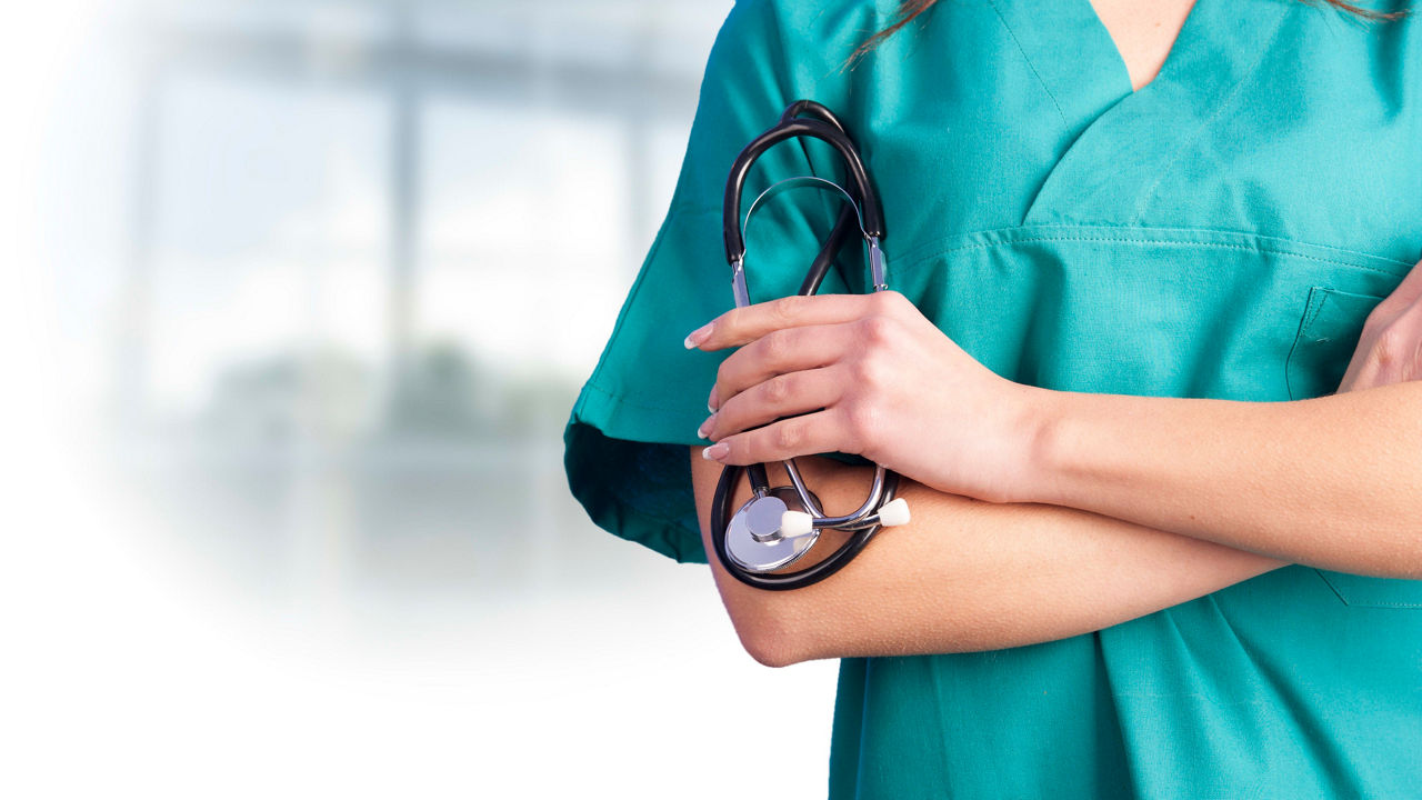 A nurse in scrubs holding a stethoscope.