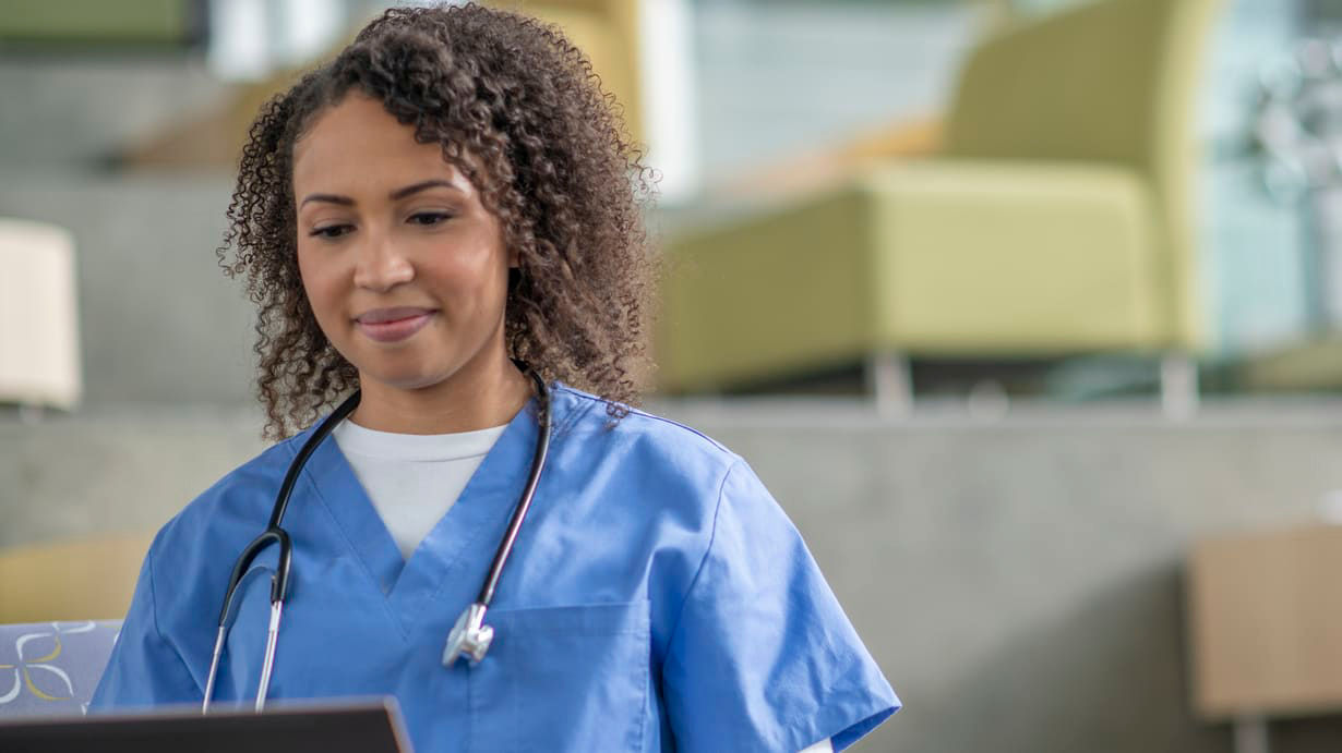 A female nurse working on a laptop in a hospital.