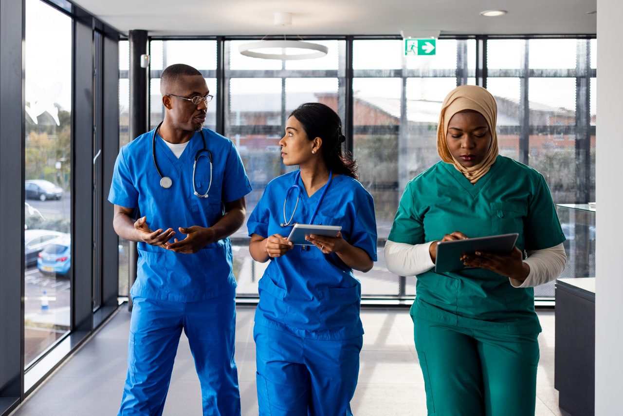 three nurses walk in hospital hallway