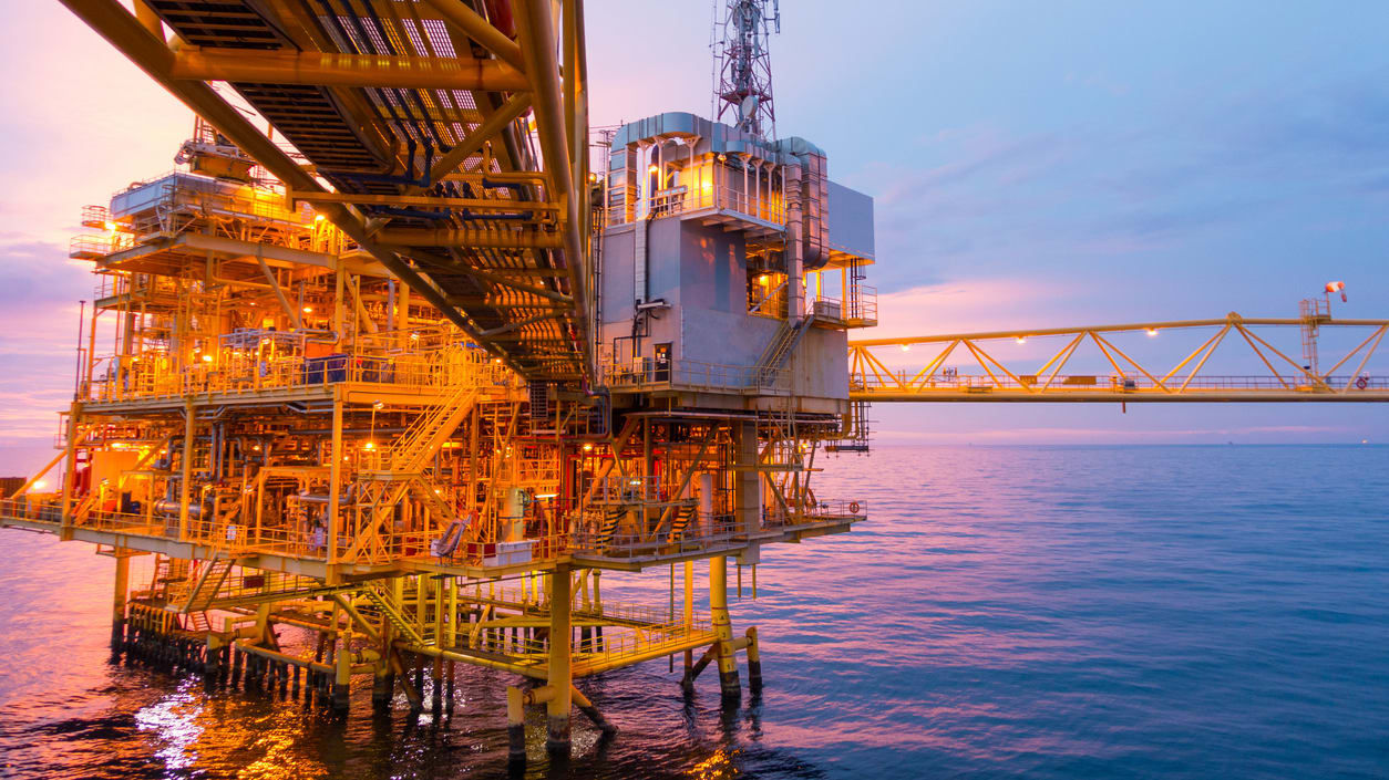 An oil platform in the ocean at dusk.