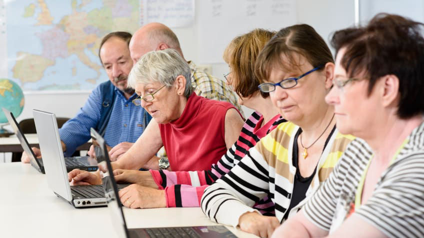 A group of people sitting around a table using laptops.