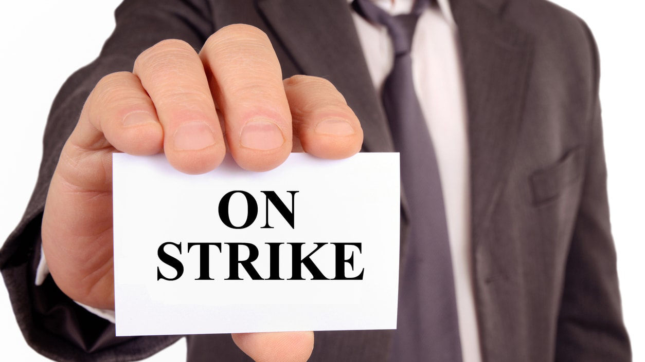 A man holding up a sign that says on strike.