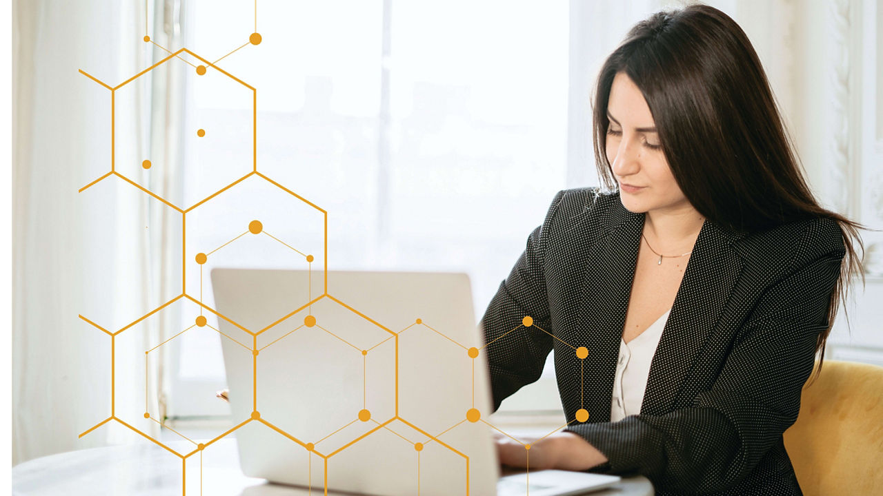 A woman is sitting at a table with a laptop in front of her.