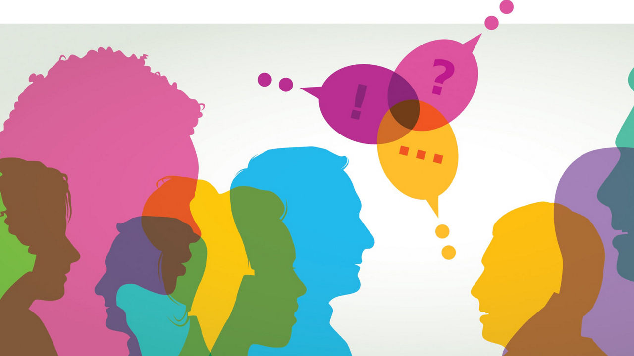 A group of people are silhouetted in front of a white background.