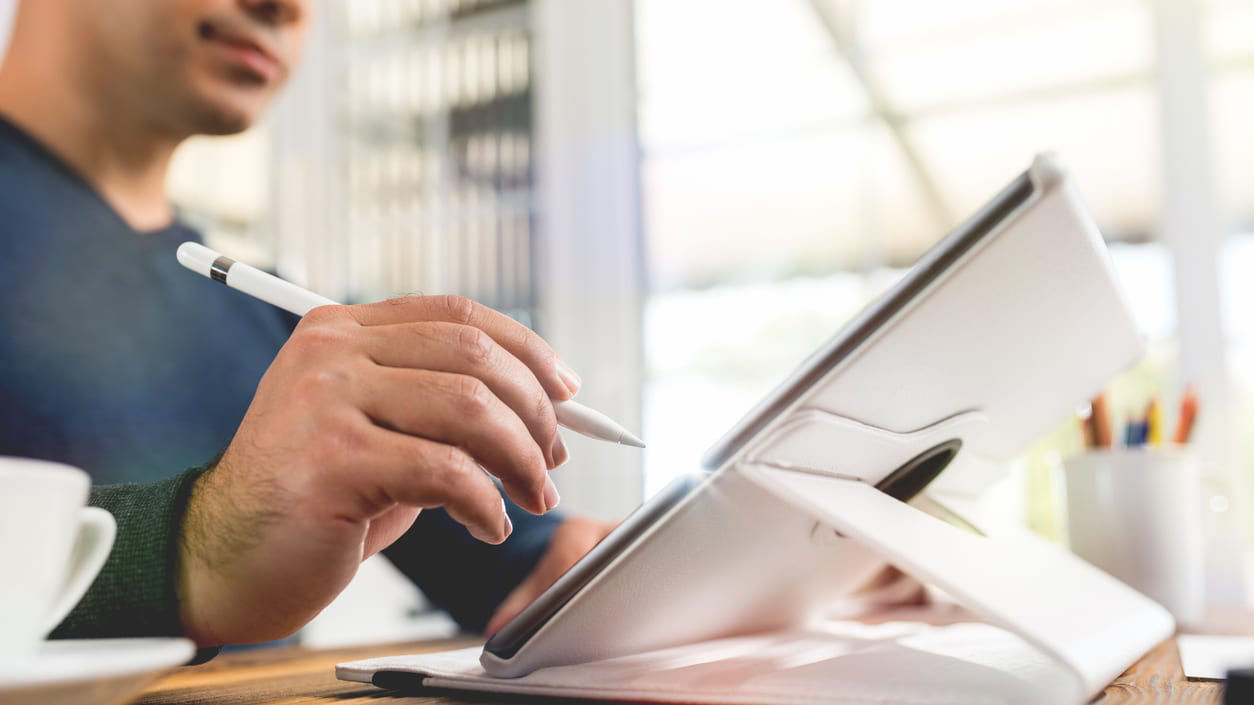 A man is using an ipad in a coffee shop.