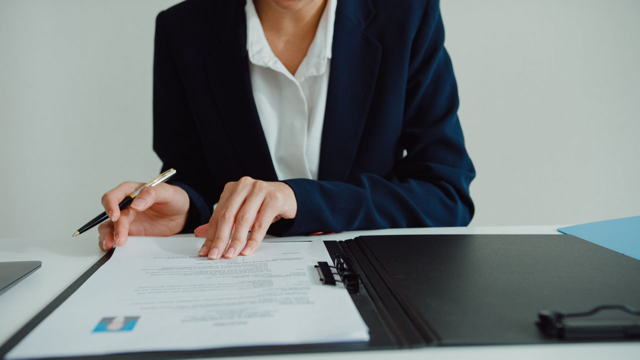 Closeup of young woman filling out forms in leather folder, sit in front of HR manager at office. Human resources