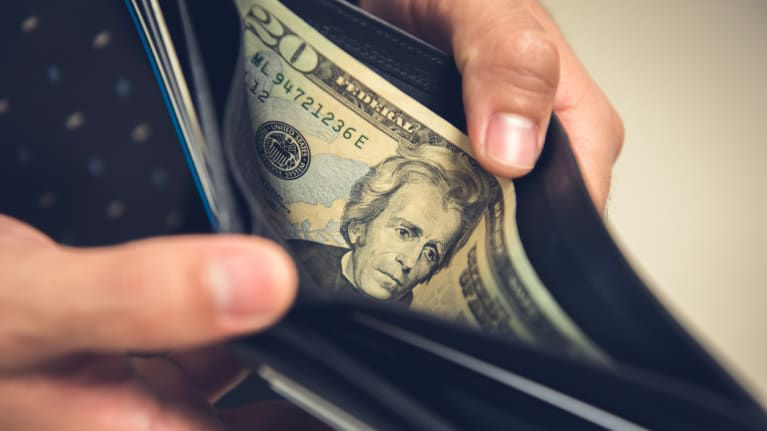 A man is holding a dollar bill in his wallet.